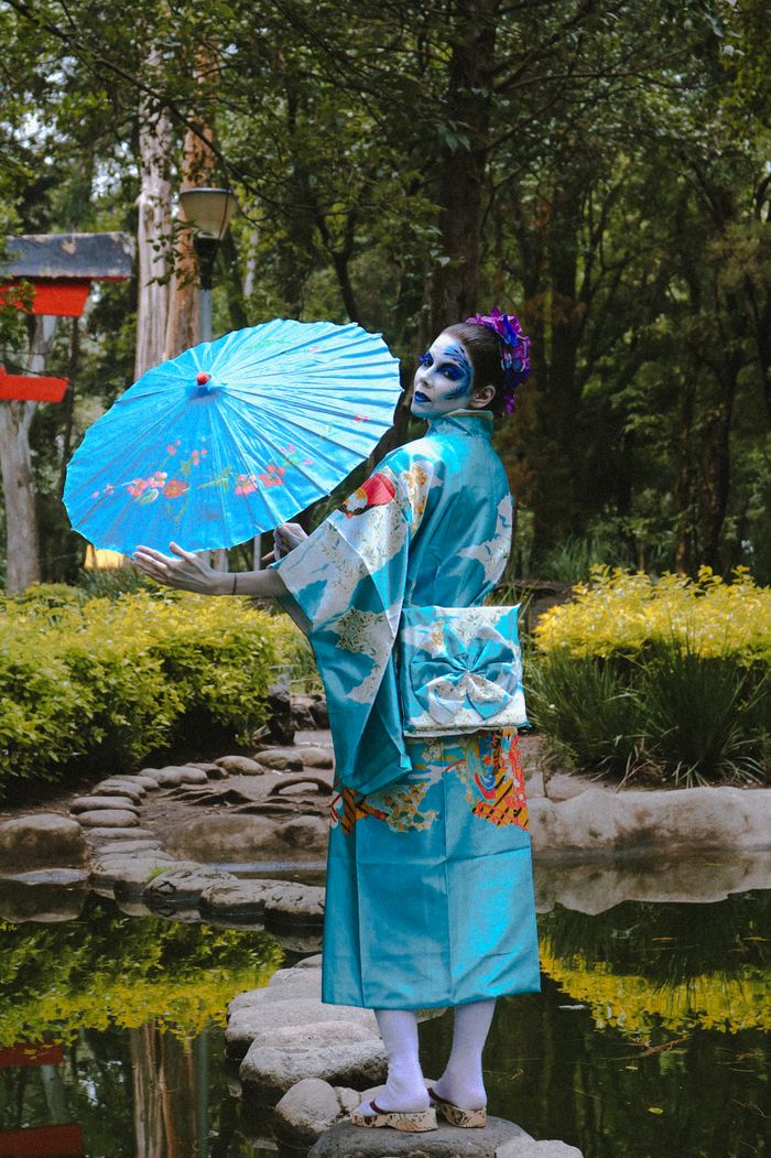 Crafting Captivating Headlines: Your awesome post title goes here Geisha in kimono holding umbrella stands in serene Japanese garden.