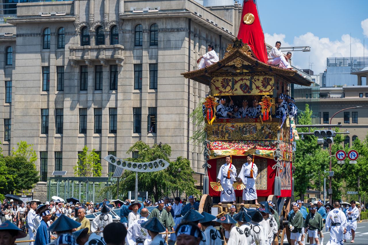 About Colorful festival float with participants in traditional attire during a sunny parade in Japan.